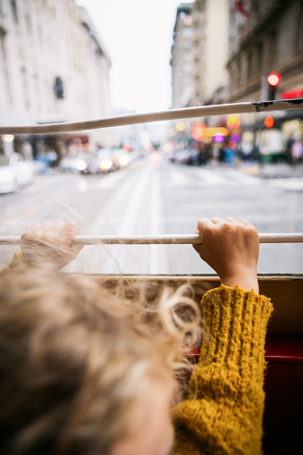 A childs hands hold onto the railing as they look out of the window on a ride  in the Hyde street cable car, downtown San Francisco Bay area.