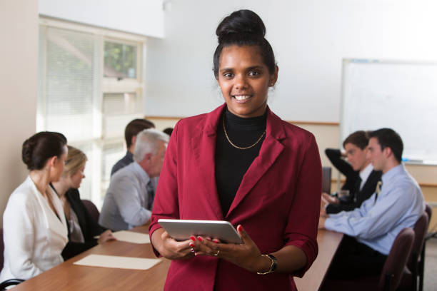 Aboriginal Tablet Computer Staff Austrtalian aboriginal woman using a tablet computer in a staff meeting or boardroom aborigine woman stock pictures, royalty-free photos & images