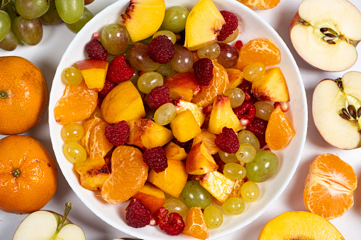 Fruit salad with sliced fruit, mixed grapes, raspberries, nectarines, tangerines and apples.