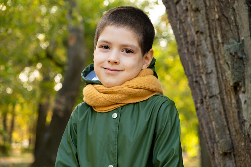 Portrait of a happy six-year-old boy in autumn forest.
