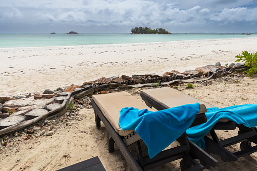 Coastal view with blue towels on chaise lounges on a summer day. Cote D'Or Beach, Praslin island, Seychelles