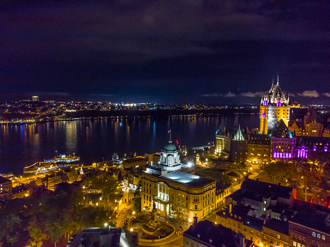 Aerial view of illuminated Chateau Frontenac Hotel and Louis St-Laurent building with St. Lawrence river during night of autumn