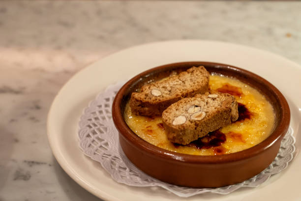 crema catalana dessert with almond toast served in brown ramekin on a white plate - custard creme brulee french cuisine crema catalana imagens e fotografias de stock