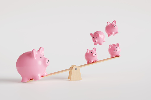 One big pink piggy bank on the left of a seesaw and four smaller money boxes on the other side. Illustration of the concept of various investment strategies