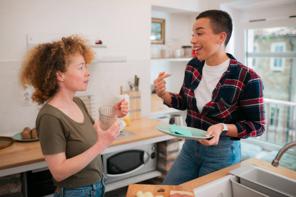 istock Happy lesbian couple talking while doing chores together in the kitchen 1733970221