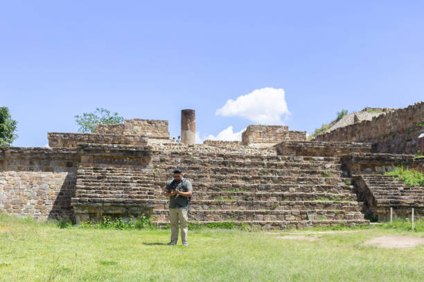 istock Mexican traveler man using smartphone in front of Monte Alban pyramid 1733981109