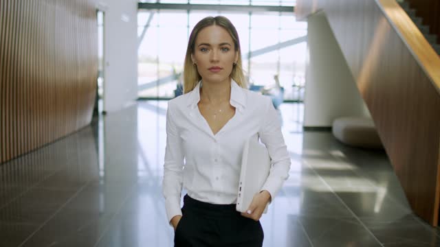 Business woman walking in office building with laptop in hand
