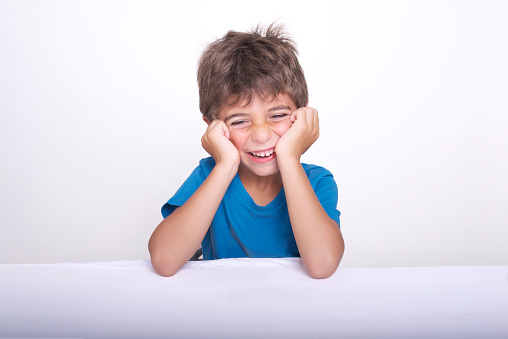 Studio photograph with white background of a beautiful 5 year old boy laughing