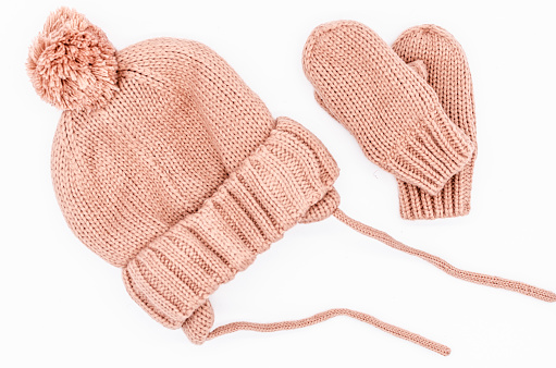A pink child's hat and gloves with white background