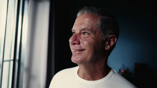 istock Happy middle-aged older man smiling while gazing out home window 1734008465