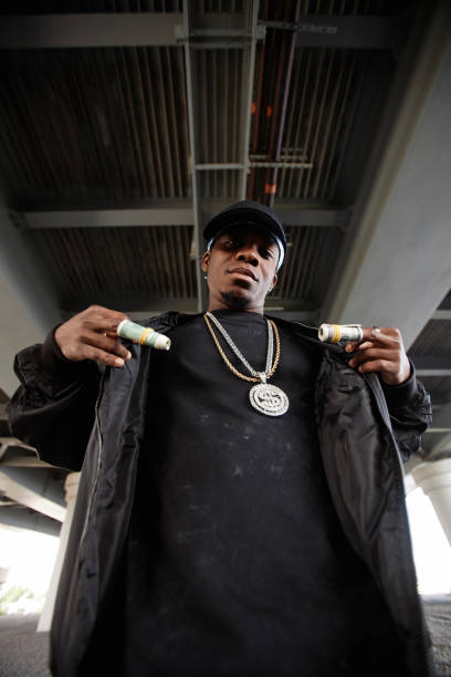 istock Young serious rapper with rolled dollar banknotes on his fingers 1734008517