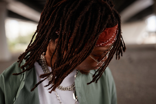 Dreadlocks of young stylish African American hip hop performer with headband on head and sunglasses standing in front of camera
