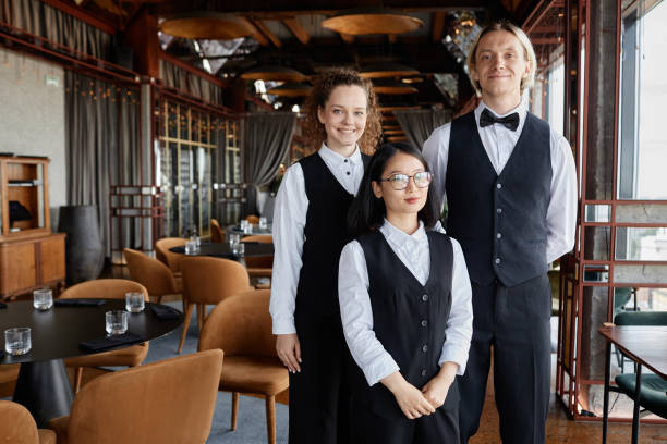 istock Three servers wearing classic uniform in restaurant and looking at camera 1734019425