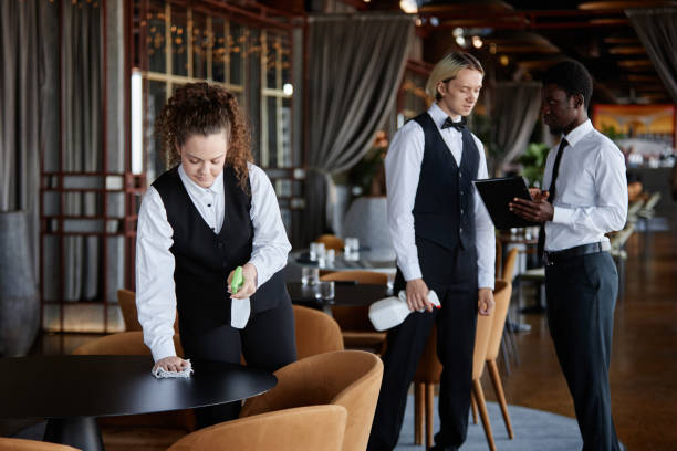 istock Group of servers in classic uniform preparing restaurant for opening 1734019450