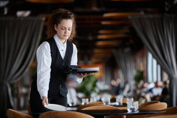 istock Young woman as female server setting table in restaurant preparing for opening 1734020002