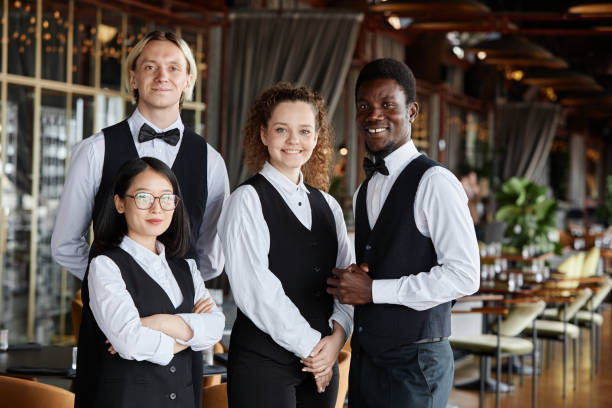 istock Diverse group of servers wearing classic tuxedo uniform smiling at camera 1734020005