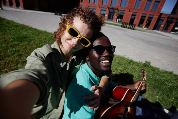 Couple taking selfie outdoors sitting on grass