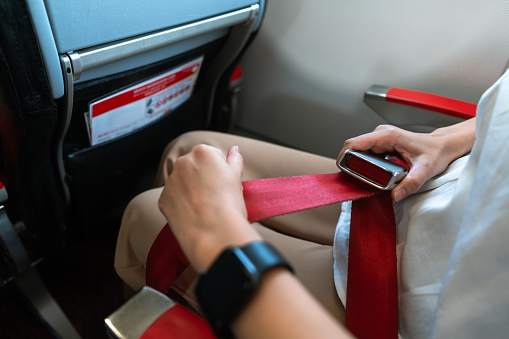 Passenger fastening seat belt while sitting on the airplane