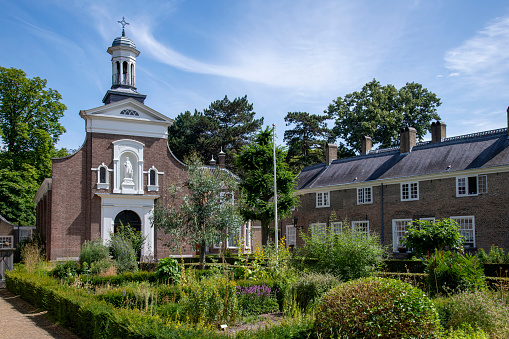Courtyard of the beguinage (Begijnhof) in Breda, the Netherlands with herb garden and surrounded by 29 small houses and Catharina churck in background