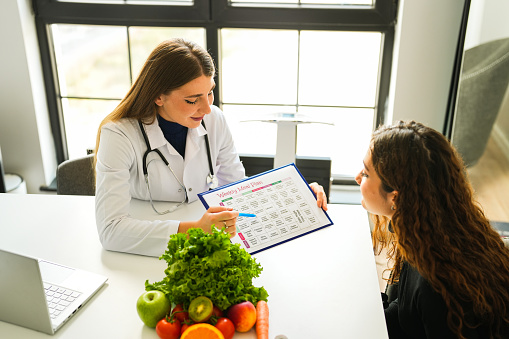 Beautiful blonde female healthy nutritionist showing her diet list to her client