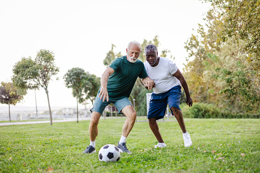 Two Diverse Senior Friends Playing Soccer Together Outdoors. Staying Fit While Having Fun