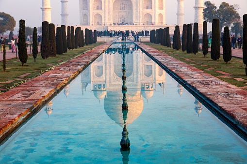 Captured in the early morning light, this image showcases the Taj Mahal as it's rarely seen, bathed in the warm glow of the rising sun. With minimal haze, the iconic white marble monument stands in sharp contrast to the sky, fully revealing its intricate design and grandeur. The photograph captures a tranquil moment at one of the world's most celebrated landmarks, offering a unique perspective of the Taj Mahal's timeless beauty.