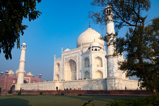 Captured in the early morning light, this image showcases the Taj Mahal as it's rarely seen, bathed in the warm glow of the rising sun. With minimal haze, the iconic white marble monument stands in sharp contrast to the sky, fully revealing its intricate design and grandeur. The photograph captures a tranquil moment at one of the world's most celebrated landmarks, offering a unique perspective of the Taj Mahal's timeless beauty.