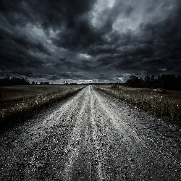 Country road in a field at storm Country road in a field at storm. Tuscany, Italy. dark road stock pictures, royalty-free photos & images