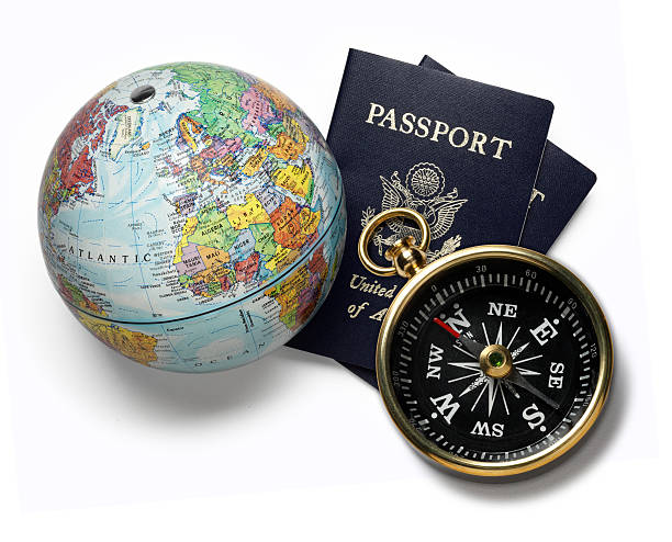 A globe and a compass sitting on two U.S. passports. White background