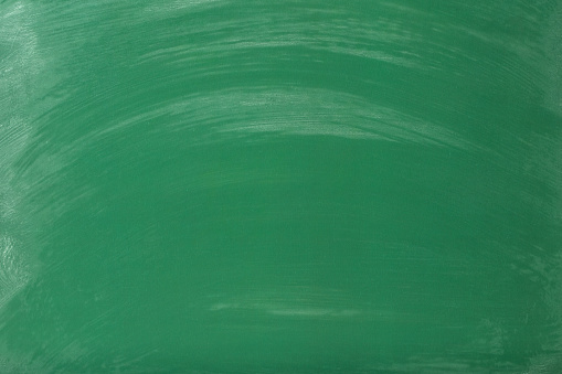 Close up of a green empty school chalkboard with chalk traces and smudges. Space for copy.