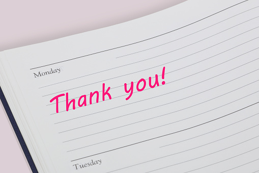 A Thank you reminder note in pink ink in a diary page