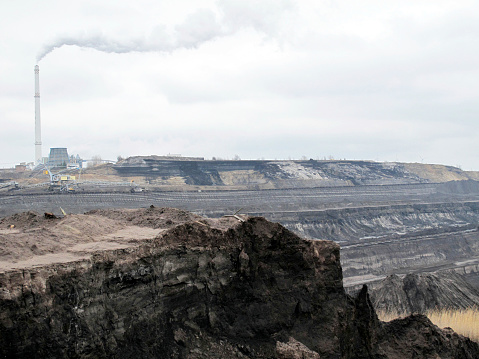open Coal strip mine with smoke stake fumes the air. 