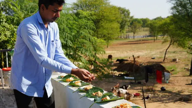 Photo of Hindu religious man offering food placed on a green leaf during a Hindu Ritual in the month of Sharada. Pitru paksha concept.