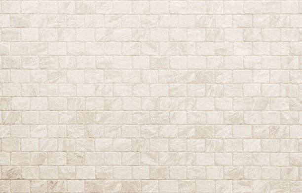 istock Empty background of wide cream brick wall texture. Beige old brown brick wall concrete or stone textured, wallpaper limestone abstract flooring. Grid uneven interior rock. Home decor design backdrop. 1734386552