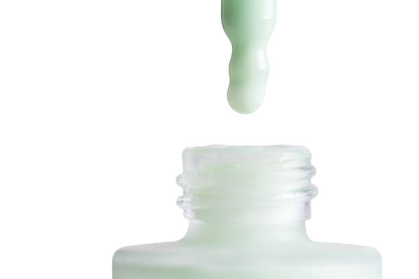 istock Drop falls from a pipette into a cosmetic bottle on white background. Pastel green face cream, makeup primer, color correcting cosmetic product, serum 1734469657