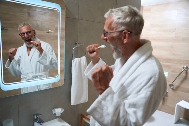 istock Elderly man in a terry robe brushes his teeth 1734471906