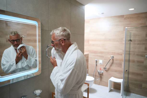 istock Elderly man in terry robe wipes his face with towel 1734471908
