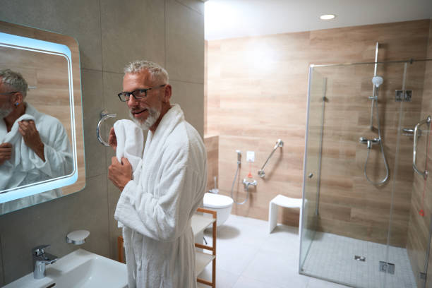 istock Old man in bathrobe wipes his face with towel 1734471909
