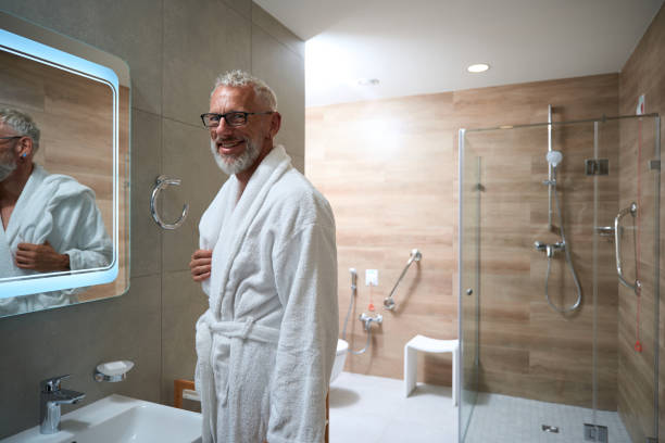 istock Old man in bathrobe in bathroom in front of mirror 1734471910