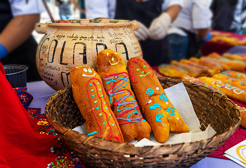 Cuenca, Ecuador - October 30, 2022: Day of the Dead event. The bread Guagua or bread figure and the drink Colada Morada in a large ceramic pot with the name on it. Breads made in the shape of a baby.