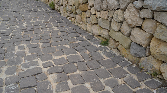old stone road made of granite stones with a wall