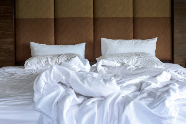 istock Unmade bed with white linens, crumpled empty and messy bed in hotel room. 1734684926