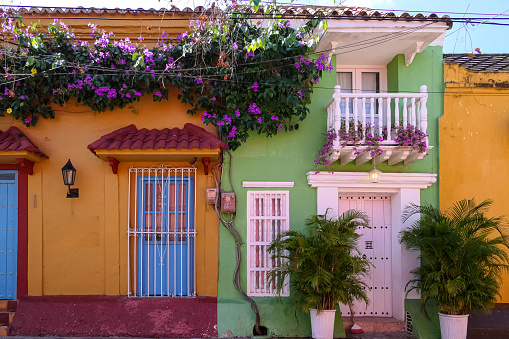 Colorful house facades with balconies and flowering plants in the Gethsemane neighborhood of Cartagena on a sunny day, Colombia