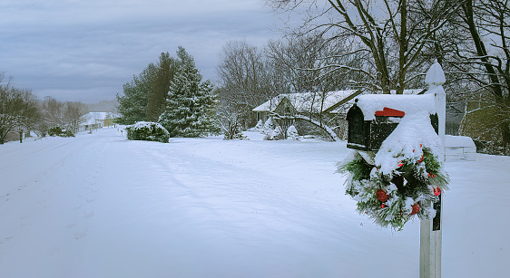 View of suburban Midwestern street covered with deep snow;  mailbox decorated with Christmas wreath in foreground