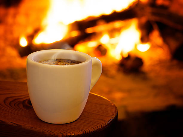 Hot smoking coffee by fireplace stock photo