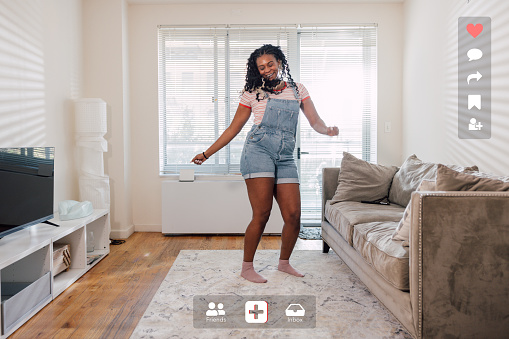 Woman dancing in the living room and recording a story to send on social media.