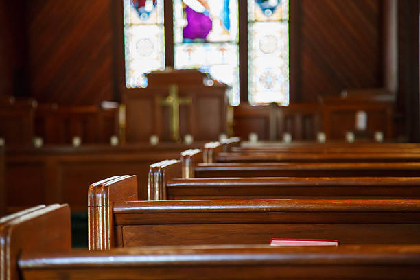 Church Pews with Stained Glass Beyond Pulpit Stained glass windows in small church with wood pews pew stock pictures, royalty-free photos & images