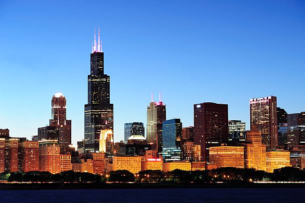 Chicago skyline at dusk Chicago city downtown urban skyline at dusk with skyscrapers over Lake Michigan with clear blue sky. willis tower stock pictures, royalty-free photos & images