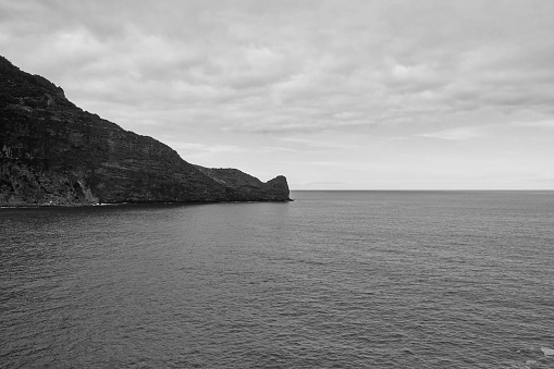 Black and white photo. View of the island's cliffs and ocean. The background of nature