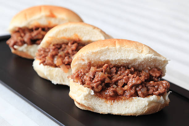 Sloppy Joe Sliders Three home-made Sloppy Joe slider sandwiches on a black serving tray. sloppy joes stock pictures, royalty-free photos & images